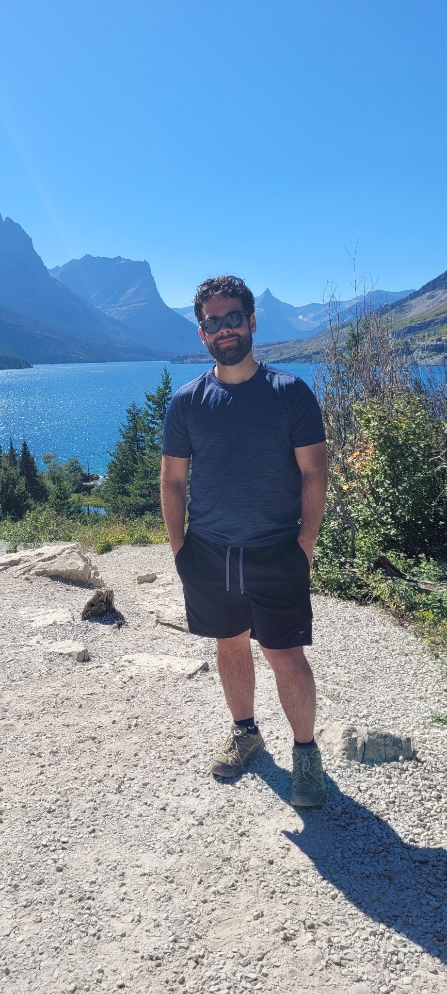 Dane Christensen standing on a hiking trail by a lake and mountains